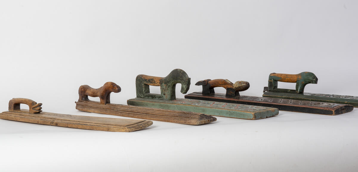 Fem mangletrær med ulike dyrefigurer til håndtak står oppstilt skrått ved siden av hverandre.