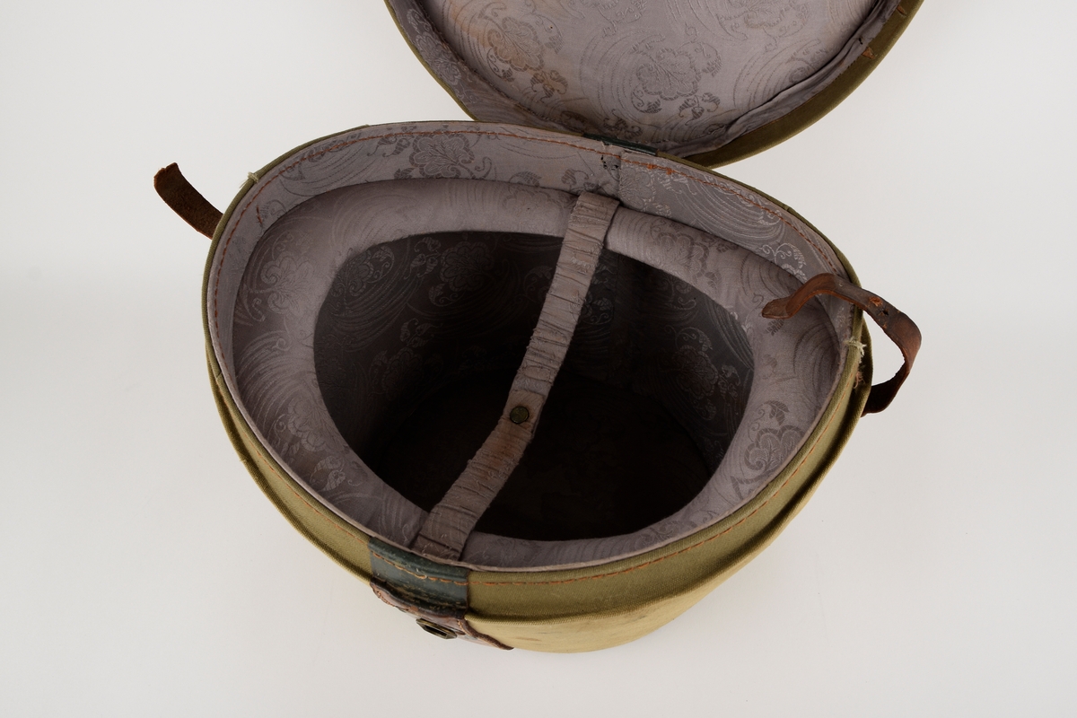 Hatteeske til flosshatt. 

Oval grunnflate. Sidene på esken skrår utover. Buet lokk. Reimer og kanter av skinn. Lokket er hengslet med skinnreim. Reimen går over lokket og ender i lås i front. Bærehåndtak av skinn på lokket, der endene har metallhemper for festing av reimer fra eskekroppen. Innvendig kledd med grå, mønstret tekstil. To reimer med trykknapp går på tvers av esken innvendig.