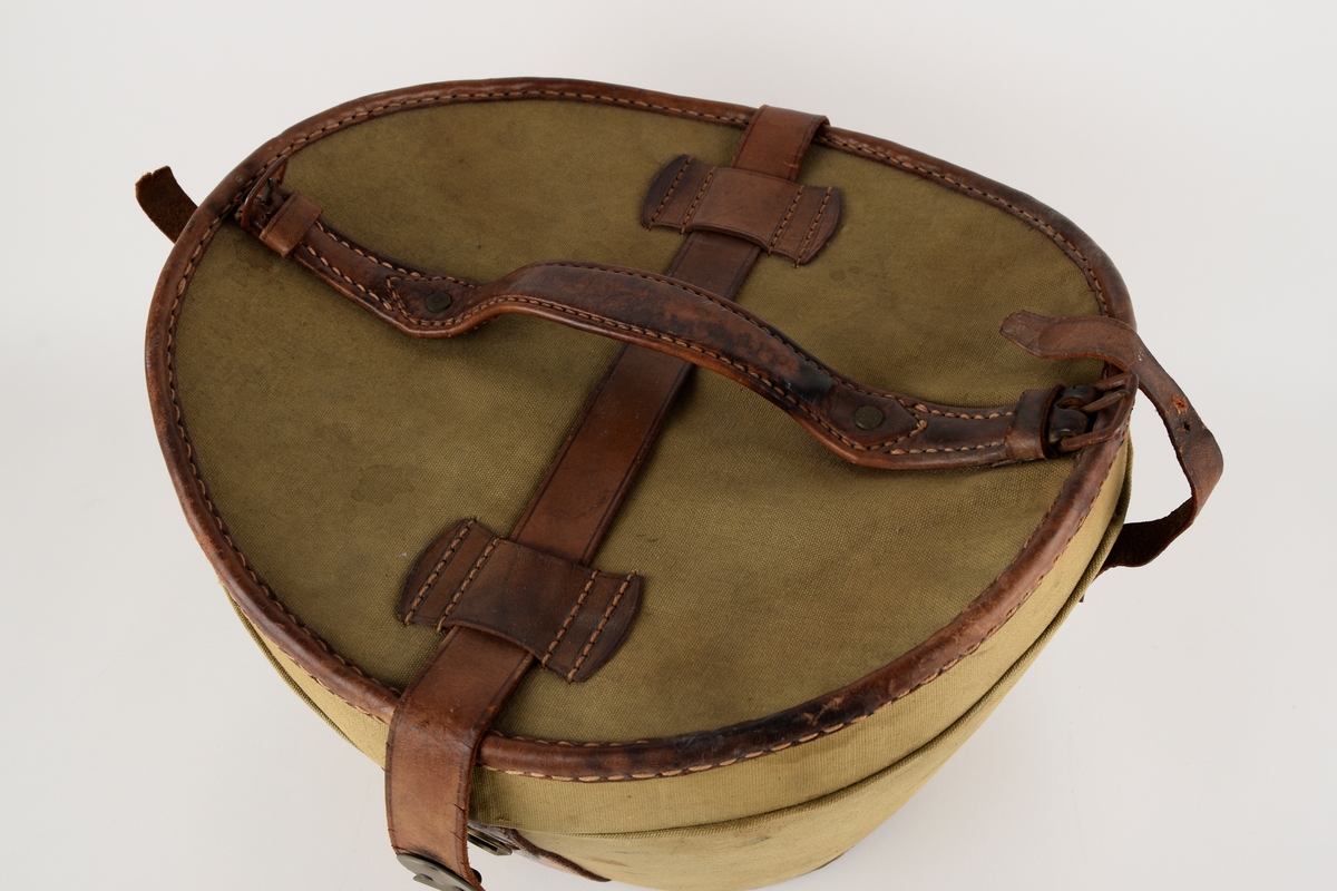 Hatteeske til flosshatt. 

Oval grunnflate. Sidene på esken skrår utover. Buet lokk. Reimer og kanter av skinn. Lokket er hengslet med skinnreim. Reimen går over lokket og ender i lås i front. Bærehåndtak av skinn på lokket, der endene har metallhemper for festing av reimer fra eskekroppen. Innvendig kledd med grå, mønstret tekstil. To reimer med trykknapp går på tvers av esken innvendig.