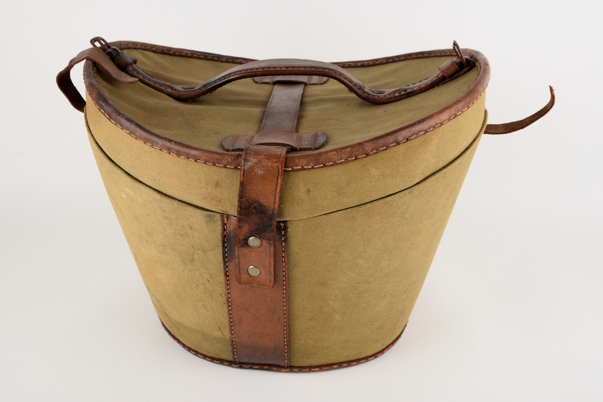 Hatteeske til flosshatt. 

Oval grunnflate. Sidene på esken skrår utover. Buet lokk. Reimer og kanter av skinn. Lokket er hengslet med skinnreim. Reimen går over lokket og ender i lås i front. Bærehåndtak av skinn på lokket, der endene har metallhemper for festing av reimer fra eskekroppen. Innvendig kledd med grå, mønstret tekstil. To reimer med trykknapp går på tvers av esken innvendig.