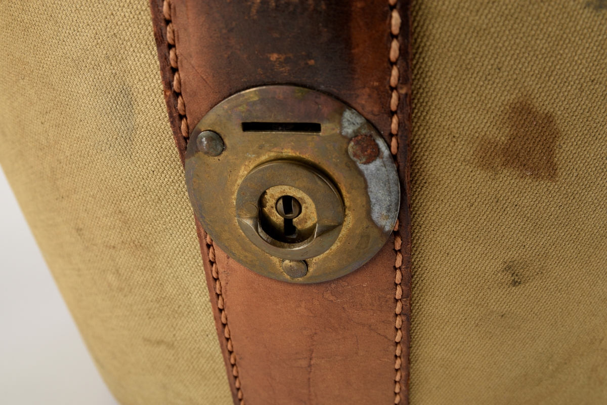 Hatteeske til flosshatt. 

Oval grunnflate. Sidene på esken skrår utover. Buet lokk. Reimer og kanter av skinn. Lokket er hengslet med skinnreim. Reimen går over lokket og ender i lås i front. Bærehåndtak av skinn på lokket, der endene har metallhemper for festing av reimer fra eskekroppen. Innvendig kledd med grå, mønstret tekstil. To reimer med trykknapp går på tvers av esken innvendig.