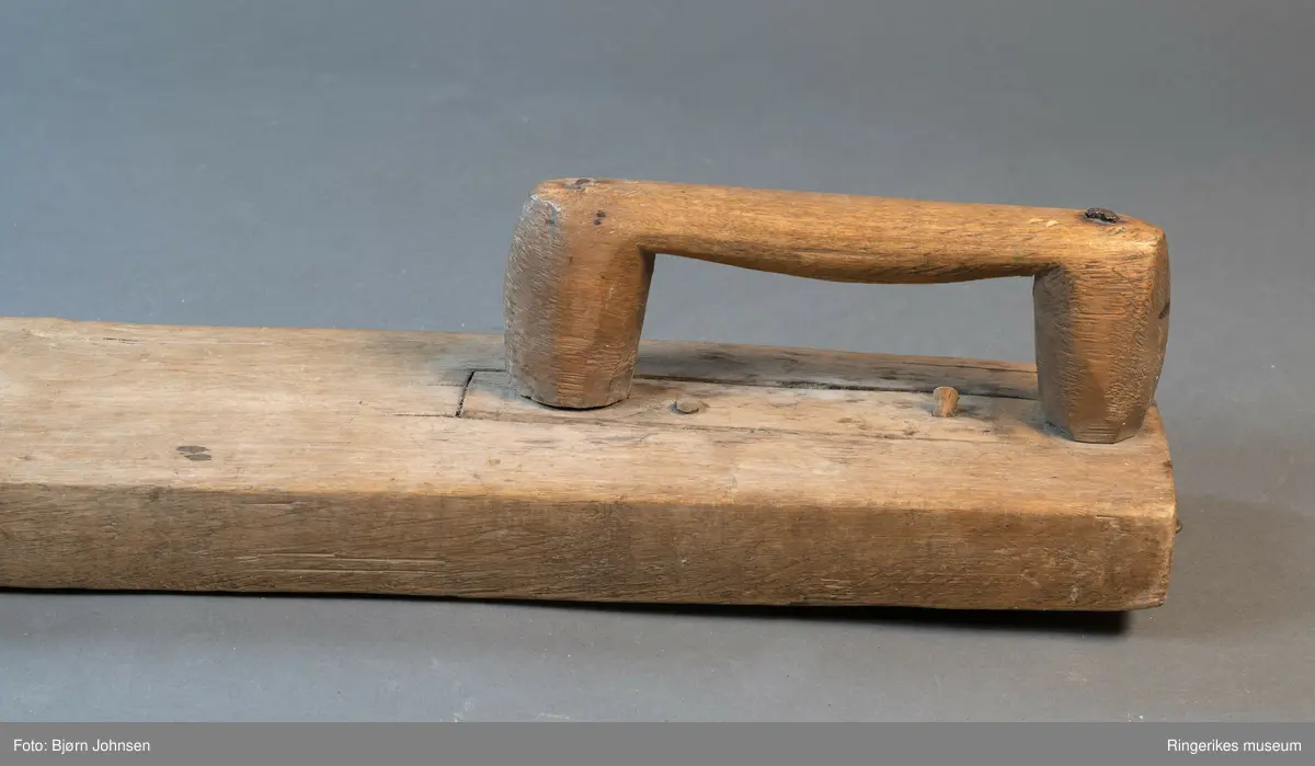 Mangletre av ubehandlet treverk. Håndtaket er festet med nagler. Mangletreet er ikke dekorert, og håndtaket har ikke spesiell utforming.