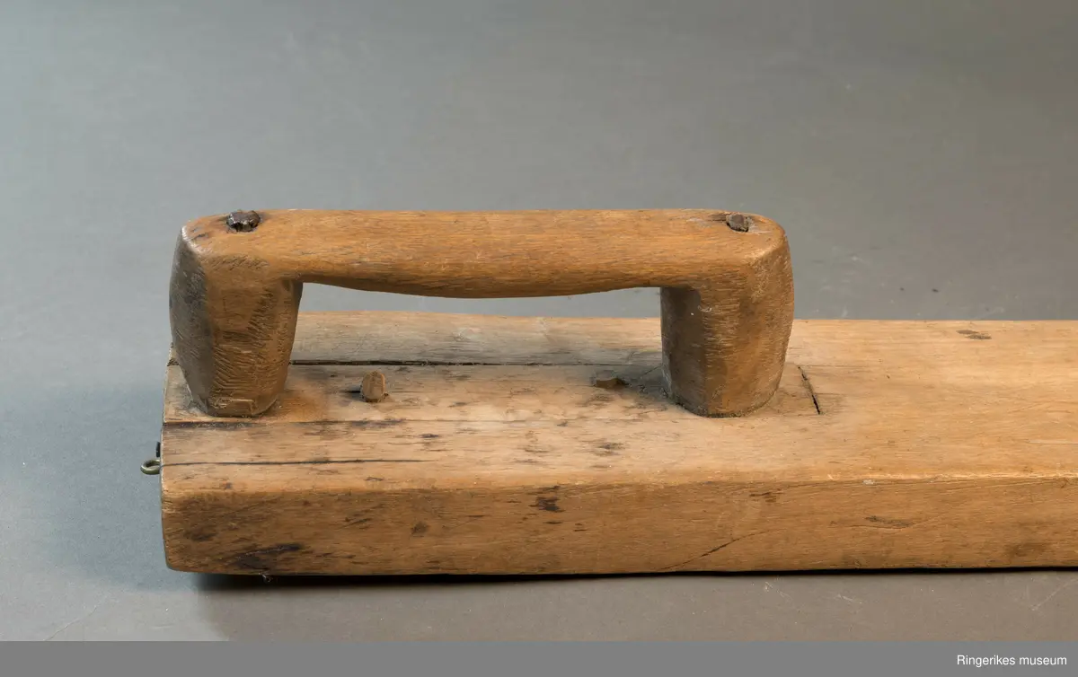 Mangletre av ubehandlet treverk. Håndtaket er festet med nagler. Mangletreet er ikke dekorert, og håndtaket har ikke spesiell utforming.