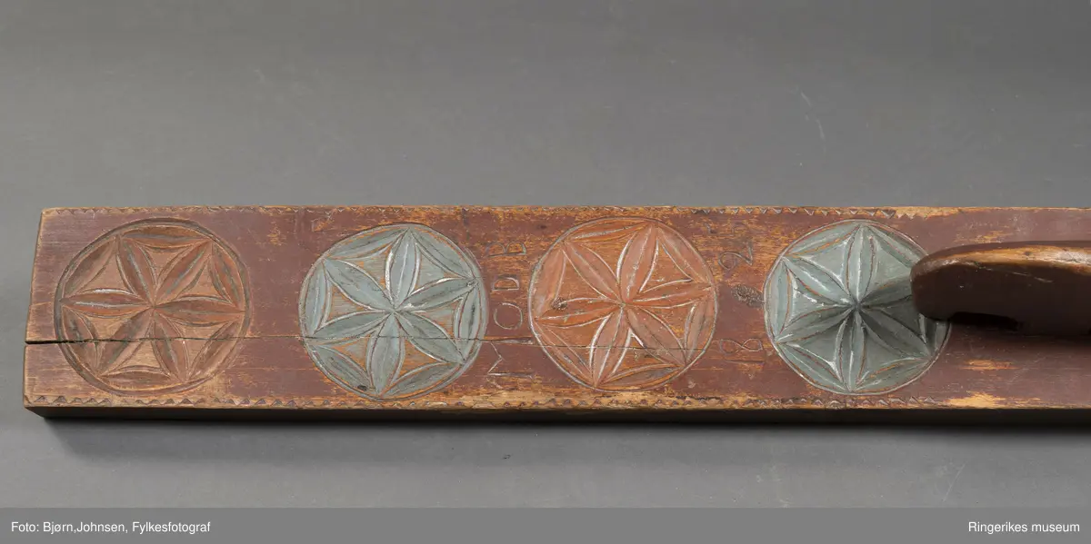 Hoveddelen av mangletreet er laget av massivt tre, med en sprekk i nederste del. Håndtaket er formet som en stilisert hest, uten detaljer som man og ører. Håndtaket er nedfelt i selve mangletreet. Oppheng med øyeskrue er laget senere. Mangletreet er dekorert med 4 store rosetter. Diameter på rosetter er på 9.3 cm. De har 6 kronblad. Rosettene er laget med karveskurd. Enkel karveskurd langs kanten.