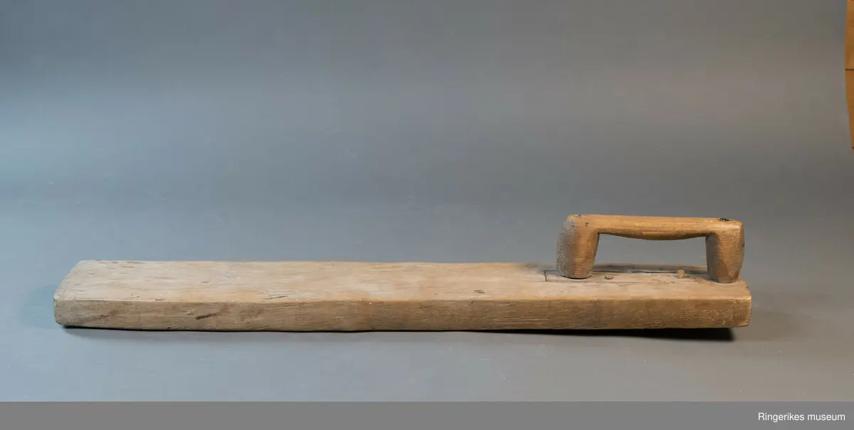 Mangletre av ubehandlet treverk. Håndtaket er festet med nagler. Mangletreet er ikke dekorert, og håndtaket har ikke spesiell utforming.