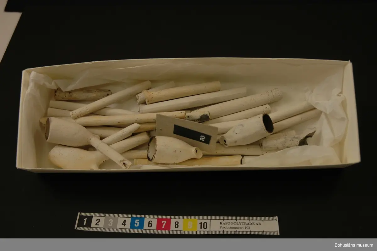 Kritpipor, fragmenterade. Huvud- och skaftdelar. Vissa med dekor. Tre skaftändar har bitmärken.

Delar av materialet ingår i Arne Åkerhagens genomgång av kritpipor i Bohuslän (2008). Datering mellan sent 1600 tal och tidigt 1700 tal. Tillverkade i England och Holland.

Landskap: Bohuslän