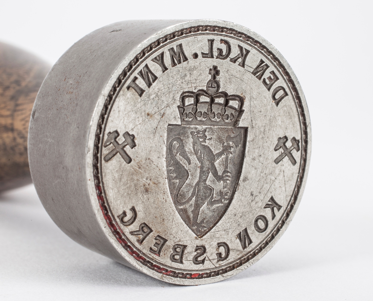 Norges riksvåpen, løve med øks og krone på ett skjold med krone over. På hver side er symbolet med hammer og feisel i kryss.