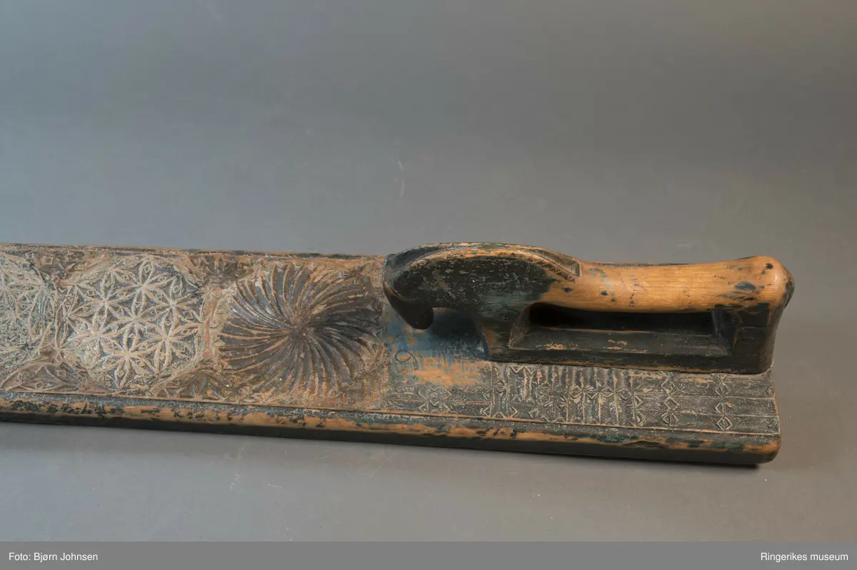 Mangletreet er dekorert med rosetter i mange forskjellige størrelser. Håndtaket er formet som en hest. Hesten har såvidt ører, øyne og munn. Hodet er stort og grovt. Øverst på mangletreet er det festet et oppheng av metall. Det er også rester av et annet oppheng, av strye eller hamp. Hesten er innfelt i mangletreet, resten av mangletreet er laget av massivt tre. Hesten har løsnet fra underlaget, ser ut som om den er festet med en treplugg. Mangletreet er dekorert med rosetter i karveskurd. Nederst er det en kvart rosett i hvert hjørne, med radius på 3 cm. Så kommer en stor rosett med diameter på 9.7 cm. Langs kanten er det to nye halve rosetter på hver side, og en i midten. Den i midten har diameter på 8 cm. De halve har diameter fra 5 cm til 7 cm. (Sett fra hesten: nederst til høyre: 5 cm, øverst til høyre: 6 cm, nederst til venstre: 6 cm, øverst til venstre: 7 cm. Under rosetten i midten står initialene OPD. Deretter kommer en stor rosett, diameter 12.5 cm. Så kommer to små, begge har diameter på 6 cm. Den største rosetten har diameter på 13.5 cm, og er nærmest hesten. Alle unntatt en rosett er dekorert med blomstermotiv. Den ene (halv rosett, øverst til høyre, 5 cm) er dekorert med buede streker. Ellers er det både i og rundt rosettene dekorert med små utskårne trekanter.