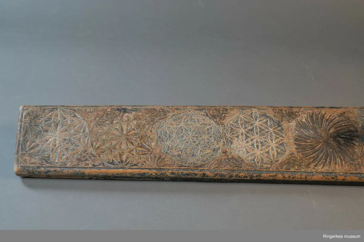 Mangletreet er dekorert med rosetter i mange forskjellige størrelser. Håndtaket er formet som en hest. Hesten har såvidt ører, øyne og munn. Hodet er stort og grovt. Øverst på mangletreet er det festet et oppheng av metall. Det er også rester av et annet oppheng, av strye eller hamp. Hesten er innfelt i mangletreet, resten av mangletreet er laget av massivt tre. Hesten har løsnet fra underlaget, ser ut som om den er festet med en treplugg. Mangletreet er dekorert med rosetter i karveskurd. Nederst er det en kvart rosett i hvert hjørne, med radius på 3 cm. Så kommer en stor rosett med diameter på 9.7 cm. Langs kanten er det to nye halve rosetter på hver side, og en i midten. Den i midten har diameter på 8 cm. De halve har diameter fra 5 cm til 7 cm. (Sett fra hesten: nederst til høyre: 5 cm, øverst til høyre: 6 cm, nederst til venstre: 6 cm, øverst til venstre: 7 cm. Under rosetten i midten står initialene OPD. Deretter kommer en stor rosett, diameter 12.5 cm. Så kommer to små, begge har diameter på 6 cm. Den største rosetten har diameter på 13.5 cm, og er nærmest hesten. Alle unntatt en rosett er dekorert med blomstermotiv. Den ene (halv rosett, øverst til høyre, 5 cm) er dekorert med buede streker. Ellers er det både i og rundt rosettene dekorert med små utskårne trekanter.