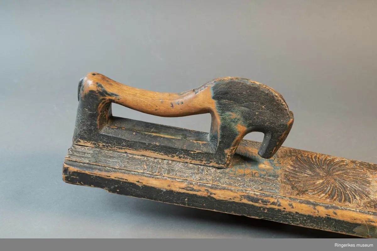 Mangletreet er dekorert med rosetter i mange forskjellige størrelser. Håndtaket er formet som en hest. Hesten har såvidt ører, øyne og munn. Hodet er stort og grovt. Øverst på mangletreet er det festet et oppheng av metall. Det er også rester av et annet oppheng, av strye eller hamp. Hesten er innfelt i mangletreet, resten av mangletreet er laget av massivt tre. Hesten har løsnet fra underlaget, ser ut som om den er festet med en treplugg. Mangletreet er dekorert med rosetter i karveskurd. Nederst er det en kvart rosett i hvert hjørne, med radius på 3 cm. Så kommer en stor rosett med diameter på 9.7 cm. Langs kanten er det to nye halve rosetter på hver side, og en i midten. Den i midten har diameter på 8 cm. De halve har diameter fra 5 cm til 7 cm. (Sett fra hesten: nederst til høyre: 5 cm, øverst til høyre: 6 cm, nederst til venstre: 6 cm, øverst til venstre: 7 cm. Under rosetten i midten står initialene OPD. Deretter kommer en stor rosett, diameter 12.5 cm. Så kommer to små, begge har diameter på 6 cm. Den største rosetten har diameter på 13.5 cm, og er nærmest hesten. Alle unntatt en rosett er dekorert med blomstermotiv. Den ene (halv rosett, øverst til høyre, 5 cm) er dekorert med buede streker. Ellers er det både i og rundt rosettene dekorert med små utskårne trekanter.