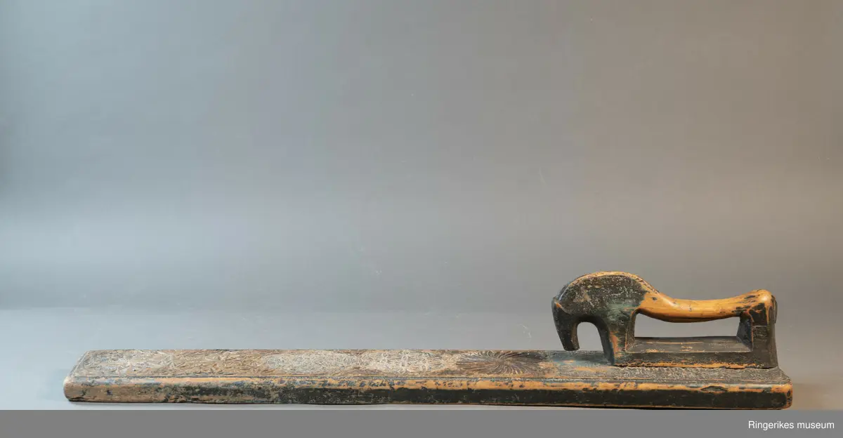 Mangletreet er dekorert med rosetter i mange forskjellige størrelser. Håndtaket er formet som en hest. Hesten har såvidt ører, øyne og munn. Hodet er stort og grovt. Øverst på mangletreet er det festet et oppheng av metall. Det er også rester av et annet oppheng, av strye eller hamp. Hesten er innfelt i mangletreet, resten av mangletreet er laget av massivt tre. Hesten har løsnet fra underlaget, ser ut som om den er festet med en treplugg. Mangletreet er dekorert med rosetter i karveskurd. Nederst er det en kvart rosett i hvert hjørne, med radius på 3 cm. Så kommer en stor rosett med diameter på 9.7 cm. Langs kanten er det to nye halve rosetter på hver side, og en i midten. Den i midten har diameter på 8 cm. De halve har diameter fra 5 cm til 7 cm. (Sett fra hesten: nederst til høyre: 5 cm, øverst til høyre: 6 cm, nederst til venstre: 6 cm, øverst til venstre: 7 cm. Under rosetten i midten står initialene OPD. Deretter kommer en stor rosett, diameter 12.5 cm. Så kommer to små, begge har diameter på 6 cm. Den største rosetten har diameter på 13.5 cm, og er nærmest hesten. Alle unntatt en rosett er dekorert med blomstermotiv. Den ene (halv rosett, øverst til høyre, 5 cm) er dekorert med buede streker. Ellers er det både i og rundt rosettene dekorert med små utskårne trekanter.