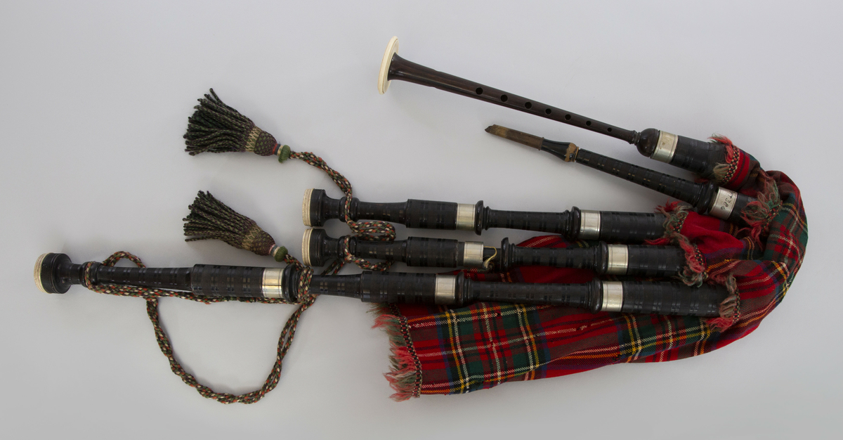 Instrument med vindsekken av skinn, trukket med skotskrutet stoff. Fire piper og ett innblåsningsrør. En skalmeie med syv hull foran og to på sidene. Skalmeien er totalt 45 cm lang og laget av mørkbrunt tre. En bordunpipe 45 cm, den andre 47,5 cm og den tredje 85 cm. Bordunpipene er i ibenholt, riflet på tvers, med sølvringer. Snor med dusk i hver ende er knytet slik at alle pipene er lenket sammen.
