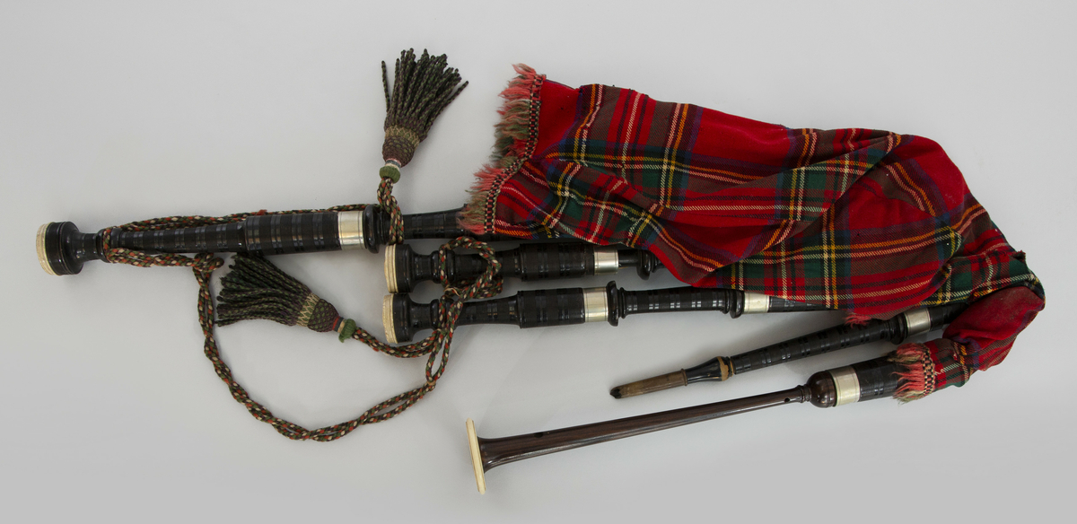 Instrument med vindsekken av skinn, trukket med skotskrutet stoff. Fire piper og ett innblåsningsrør. En skalmeie med syv hull foran og to på sidene. Skalmeien er totalt 45 cm lang og laget av mørkbrunt tre. En bordunpipe 45 cm, den andre 47,5 cm og den tredje 85 cm. Bordunpipene er i ibenholt, riflet på tvers, med sølvringer. Snor med dusk i hver ende er knytet slik at alle pipene er lenket sammen.