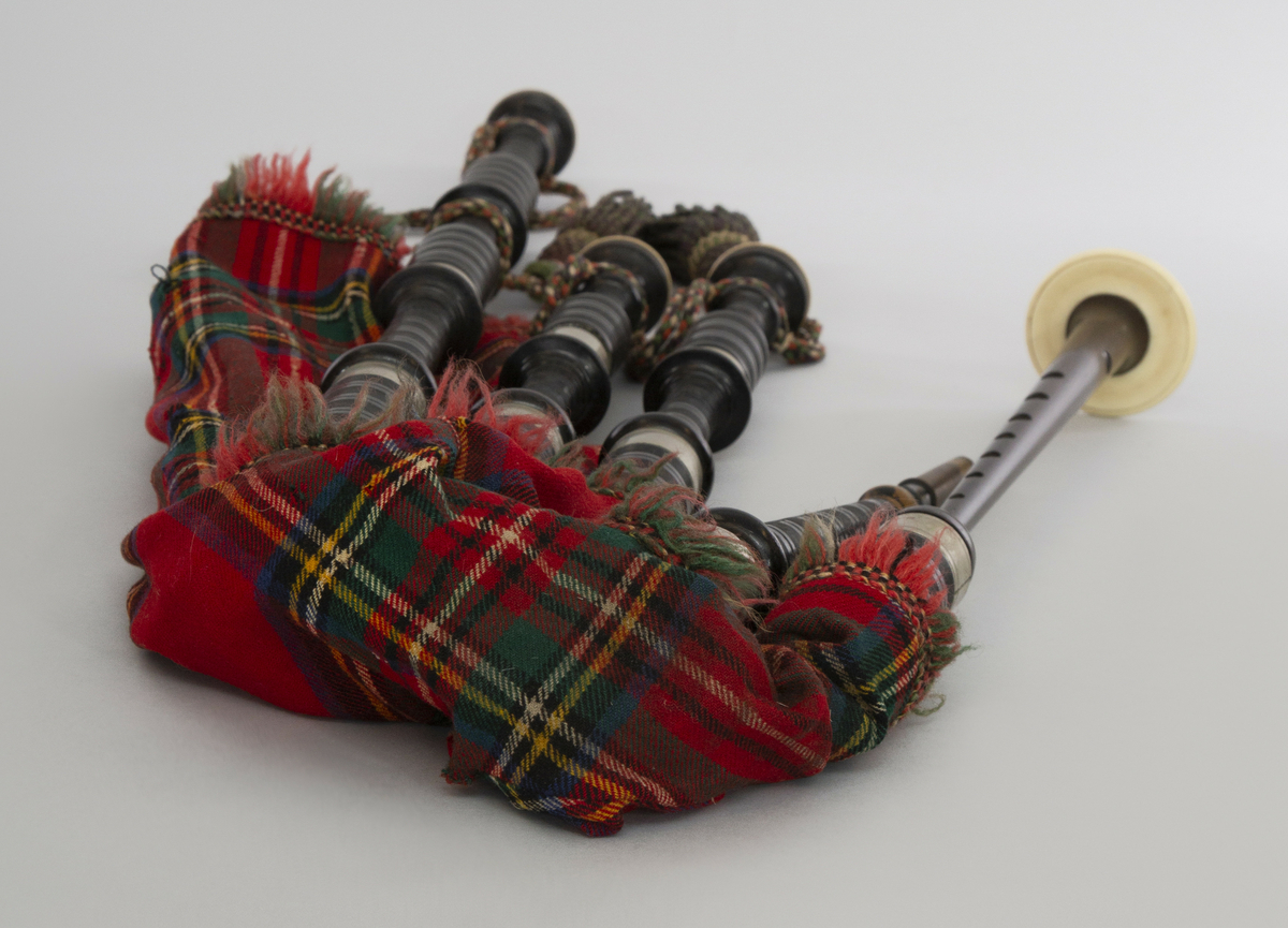 Instrument med vindsekken av skinn, trukket med skotskrutet stoff. Fire piper og ett innblåsningsrør. En skalmeie med syv hull foran og to på sidene. Skalmeien er totalt 45 cm lang og laget av mørkbrunt tre. En bordunpipe 45 cm, den andre 47,5 cm og den tredje 85 cm. Bordunpipene er i ibenholt, riflet på tvers, med sølvringer. Snor med dusk i hver ende er knytet slik at alle pipene er lenket sammen.