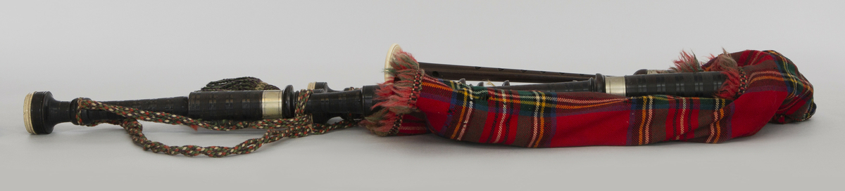 Instrument med vindsekken av skinn, trukket med skotskrutet stoff. Fire piper og ett innblåsningsrør. En skalmeie med syv hull foran og to på sidene. Skalmeien er totalt 45 cm lang og laget av mørkbrunt tre. En bordunpipe 45 cm, den andre 47,5 cm og den tredje 85 cm. Bordunpipene er i ibenholt, riflet på tvers, med sølvringer. Snor med dusk i hver ende er knytet slik at alle pipene er lenket sammen.