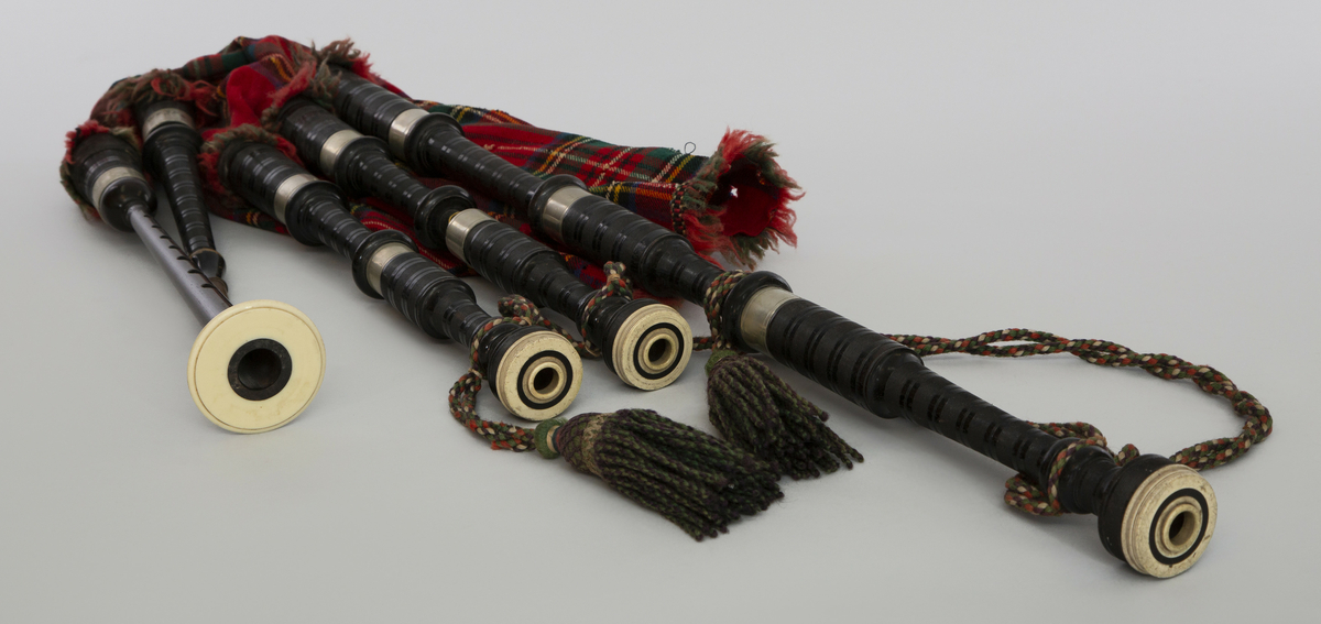 Instrument med vindsekken av skinn, trukket med skotskrutet stoff. Fire piper og ett innblåsningsrør. En skalmeie med syv hull foran og to på sidene. Skalmeien er totalt 45 cm lang og laget av mørkbrunt tre. En bordunpipe 45 cm, den andre 47,5 cm og den tredje 85 cm. Bordunpipene er i ibenholt, riflet på tvers, med sølvringer. Snor med dusk i hver ende er knytet slik at alle pipene er lenket sammen.