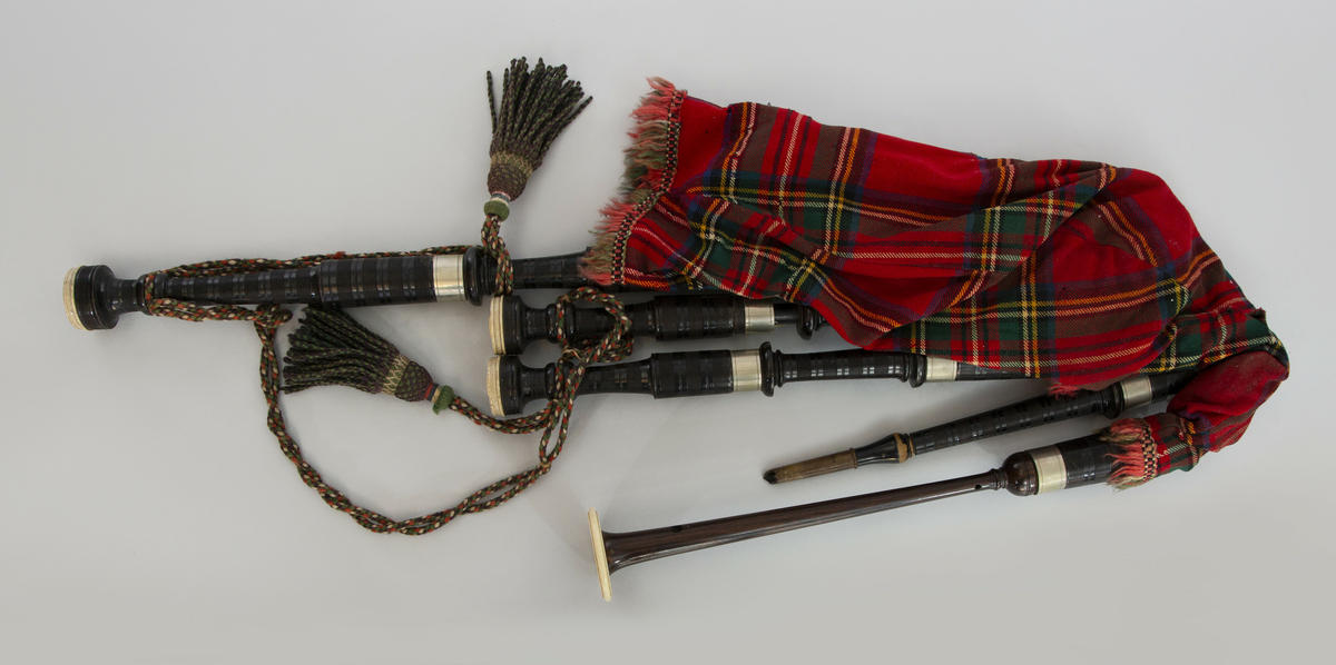 Instrument med vindsekken av skinn, trukket med skotskrutet stoff. Fire piper og ett innblåsningsrør. En skalmeie med syv hull foran og to på sidene. Skalmeien er totalt 45 cm lang og laget av mørkbrunt tre. En bordunpipe 45 cm, den andre 47,5 cm og den tredje 85 cm. Bordunpipene er i ibenholt, riflet på tvers, med sølvringer. Snor med dusk i hver ende er knytet slik at alle pipene er lenket sammen.