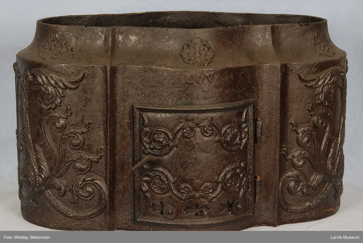 Rokokko-ornamentikk på sidene og bak også på dør. 6 felter med rosetter.