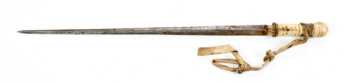 Stokk med døllebajonettklinge. Klingen er dekorert med gravering og har håndtak av bein med en lærreim. Stokken er av tre med et shellaklag og med messingbeslag. 
