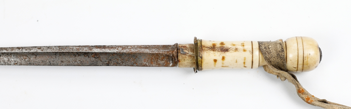 Stokk med døllebajonettklinge. Klingen er dekorert med gravering og har håndtak av bein med en lærreim. Stokken er av tre med et shellaklag og med messingbeslag. 