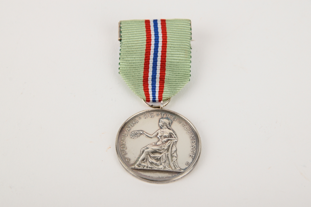 Et eksemplar av "Medaljen for lang og tro tjeneste" i originalt etui. 

Sirkulær medalje med ordensbånd, oppbevart i rektangulært etui.