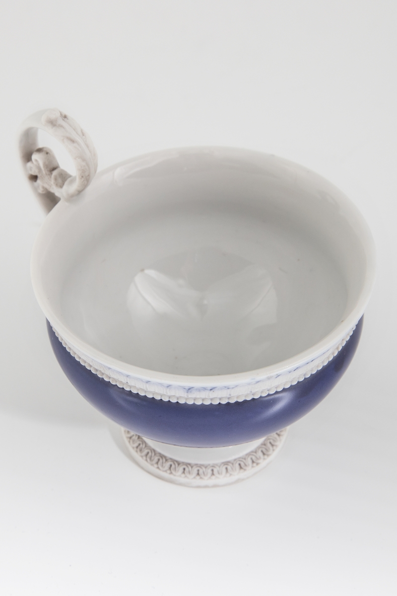 Koppen er dekorert med antikke ornamenter: Et bånd med ionisk kymation (eggstav) langs randen og nederst på koppens korpus. Rundt foten et bånd med lesbisk kymation. Håntak formet som et akantusblad. Et bånd med ionisk kymation rundt speilet på skålen.