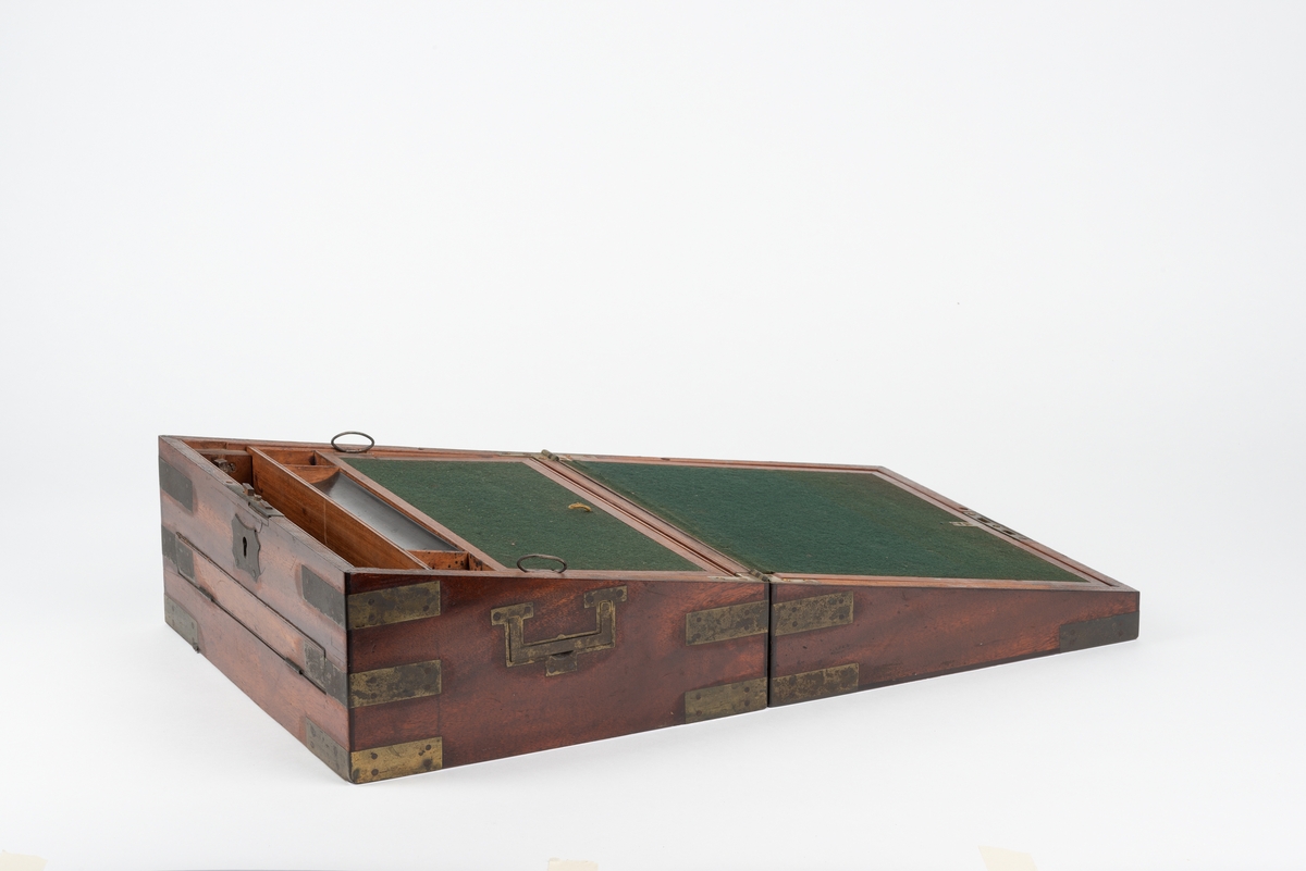 Rektangulær trekasse med kopieringsmaskin. Kassen har flere rom og skuffer. Inni lokket er det et rom som kan åpnes ved å løfte på en klaff. Dette rommet kan være til oppbevaring av papir. Klaffen er foret med filt på den ene siden. Nede i kassa er det en liten, løs trekasse som kan tas ut. I denne er det plass til to blekkhus og pennesplitter. Under den løse trekassen er det et rom med en valse i metall. Valsen kan dreies rundt med en løs sveiv. I bunnen har kassen en uttrekkbar skuff. Kassen har beslag og bærehåndtak i metall. Til kopieringsmaskinen følger det med en løs sveiv, et løst håndtak, et blekkhus og en liten kost.