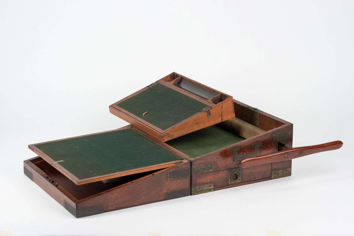 Rektangulær trekasse med kopieringsmaskin. Kassen har flere rom og skuffer. Inni lokket er det et rom som kan åpnes ved å løfte på en klaff. Dette rommet kan være til oppbevaring av papir. Klaffen er foret med filt på den ene siden. Nede i kassa er det en liten, løs trekasse som kan tas ut. I denne er det plass til to blekkhus og pennesplitter. Under den løse trekassen er det et rom med en valse i metall. Valsen kan dreies rundt med en løs sveiv. I bunnen har kassen en uttrekkbar skuff. Kassen har beslag og bærehåndtak i metall. Til kopieringsmaskinen følger det med en løs sveiv, et løst håndtak, et blekkhus og en liten kost.