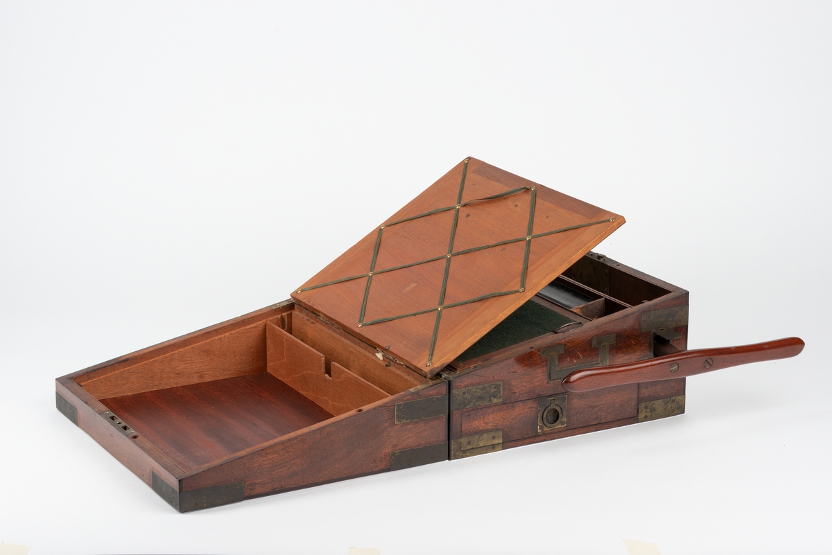 Rektangulær trekasse med kopieringsmaskin. Kassen har flere rom og skuffer. Inni lokket er det et rom som kan åpnes ved å løfte på en klaff. Dette rommet kan være til oppbevaring av papir. Klaffen er foret med filt på den ene siden. Nede i kassa er det en liten, løs trekasse som kan tas ut. I denne er det plass til to blekkhus og pennesplitter. Under den løse trekassen er det et rom med en valse i metall. Valsen kan dreies rundt med en løs sveiv. I bunnen har kassen en uttrekkbar skuff. Kassen har beslag og bærehåndtak i metall. Til kopieringsmaskinen følger det med en løs sveiv, et løst håndtak, et blekkhus og en liten kost.