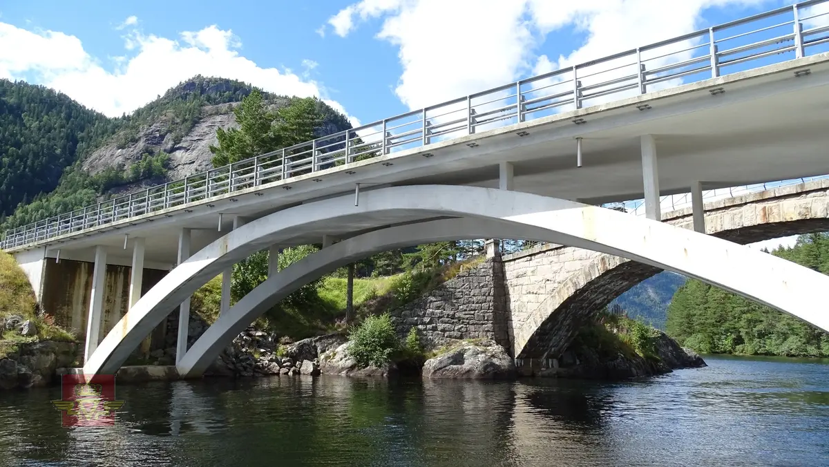 Brumiljø med 5 bruer og sluseanlegg. Bruene inngår i "Nasjonal verneplan for veger, bruer og vegrelaterte kulturminner". Forskiftsfredet etter kulturminnelovens § 22a den 17.04.2008. Bildet viser Storstraumen bru bygd i 1963. Brua i bruk for Rv 9. I forgrunnen sees den ene sluseporten. Slusen restaurert og brukes i sommerhalvåret av veterandampskipet Bjoren. (Informant: Harald Tallaksen)

Nr. 51-53 Storstraumen vegmiljø, side 70, jf. "Nasjonal verneplan for veger, bruer og vegrelaterte kulturminner". Statens vegvesen - Region Sør. Utgitt 2002.
Se Nedlastinger lenger ned på siden.