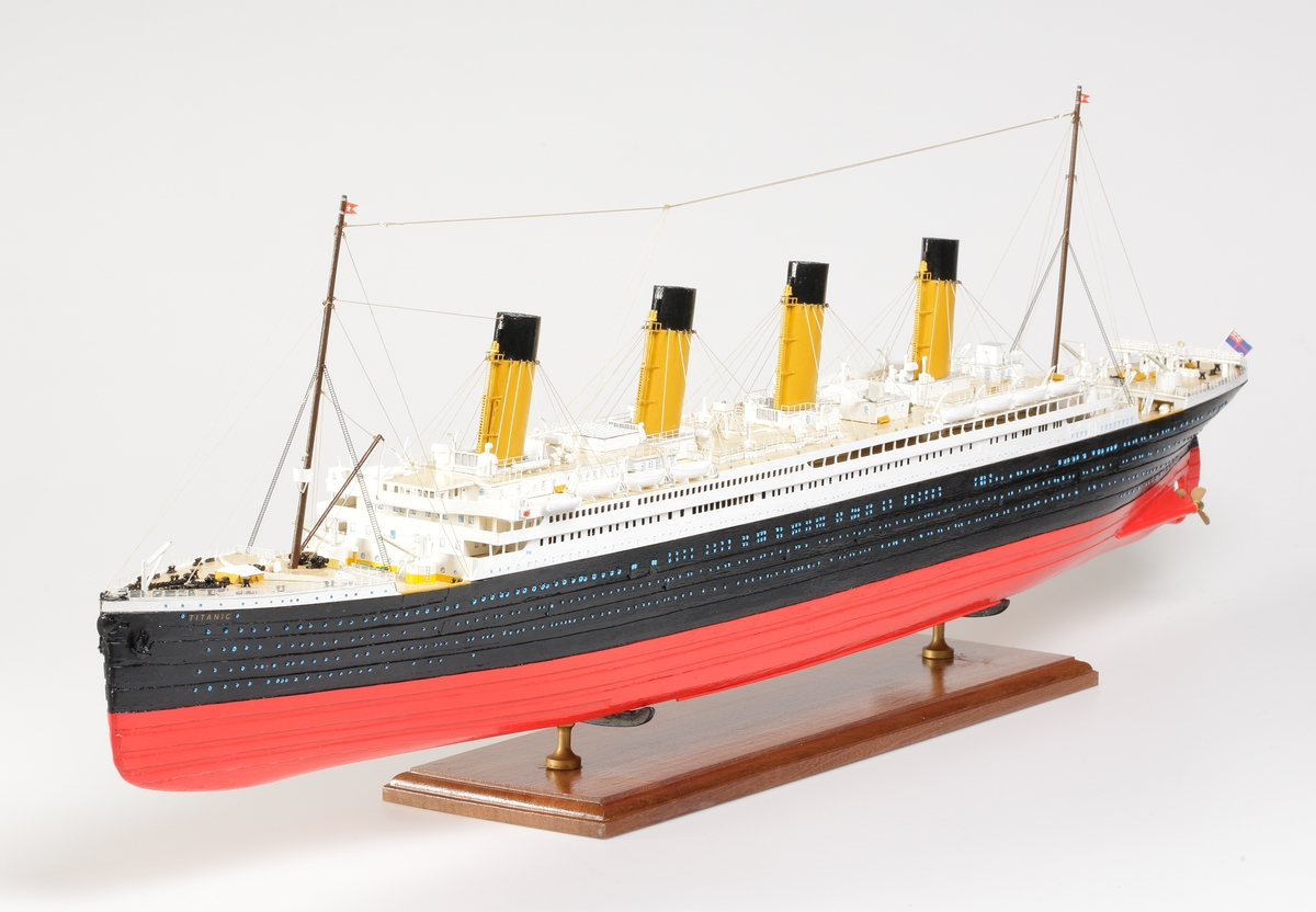 Oceanångare (Titanic) i trä och textil. Skrovet är målat i rött, svart och vitt, samt blått som är önsterventilerna. Däcket är trävitt och lackerat. På däcket finns detaljerat all utrustning såsom kranar, livbåtar, hytter, soffor och ventiler. Där finns fyra stora skorstenar med toppar i svart, och två större master med White Star Lines röda vimplar i toppen. Master och skorstenar är förbundna med linor i textil. I aktern är det tre propellrar och ett stort roder under vattenlinjen. Uppe vid relingen finns också en stång med en engelsk statsflagga. Modellen står på en brunbetsad platta i trä.