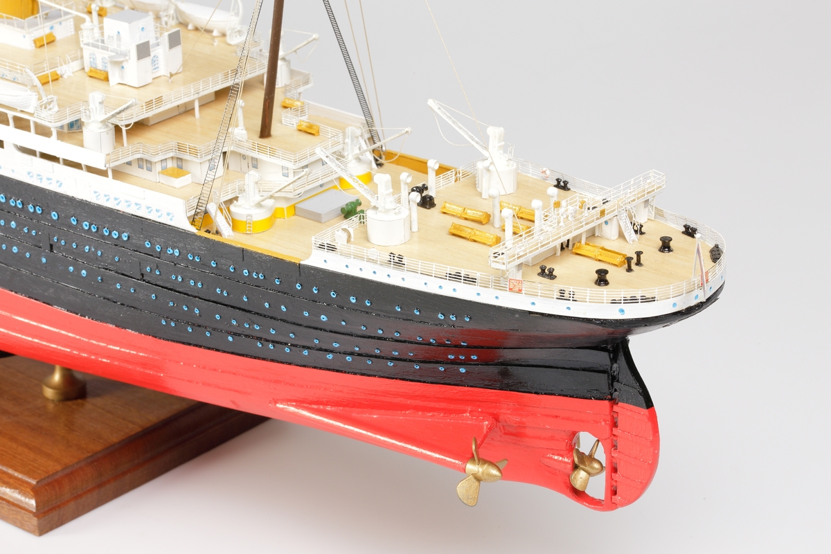 Oceanångare (Titanic) i trä och textil. Skrovet är målat i rött, svart och vitt, samt blått som är önsterventilerna. Däcket är trävitt och lackerat. På däcket finns detaljerat all utrustning såsom kranar, livbåtar, hytter, soffor och ventiler. Där finns fyra stora skorstenar med toppar i svart, och två större master med White Star Lines röda vimplar i toppen. Master och skorstenar är förbundna med linor i textil. I aktern är det tre propellrar och ett stort roder under vattenlinjen. Uppe vid relingen finns också en stång med en engelsk statsflagga. Modellen står på en brunbetsad platta i trä.