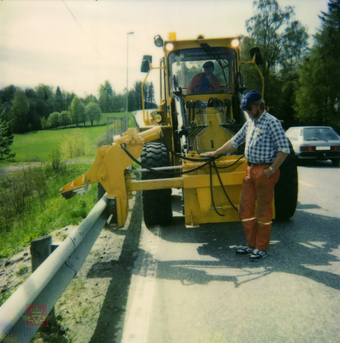 Vedlikehold av guardrail langs E18. En arbeider demonstrerer rettemaskin for guardrail som er påmontert en hjullaster. Stedsnavn Brekka i Arendal.