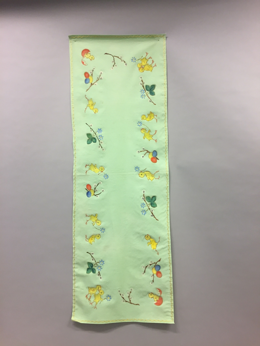 Løpar med trykt motiv. Kyllingar, blåveis og seljekvistar med "gåsungar". Handbrodert kant rundt alle sidene.