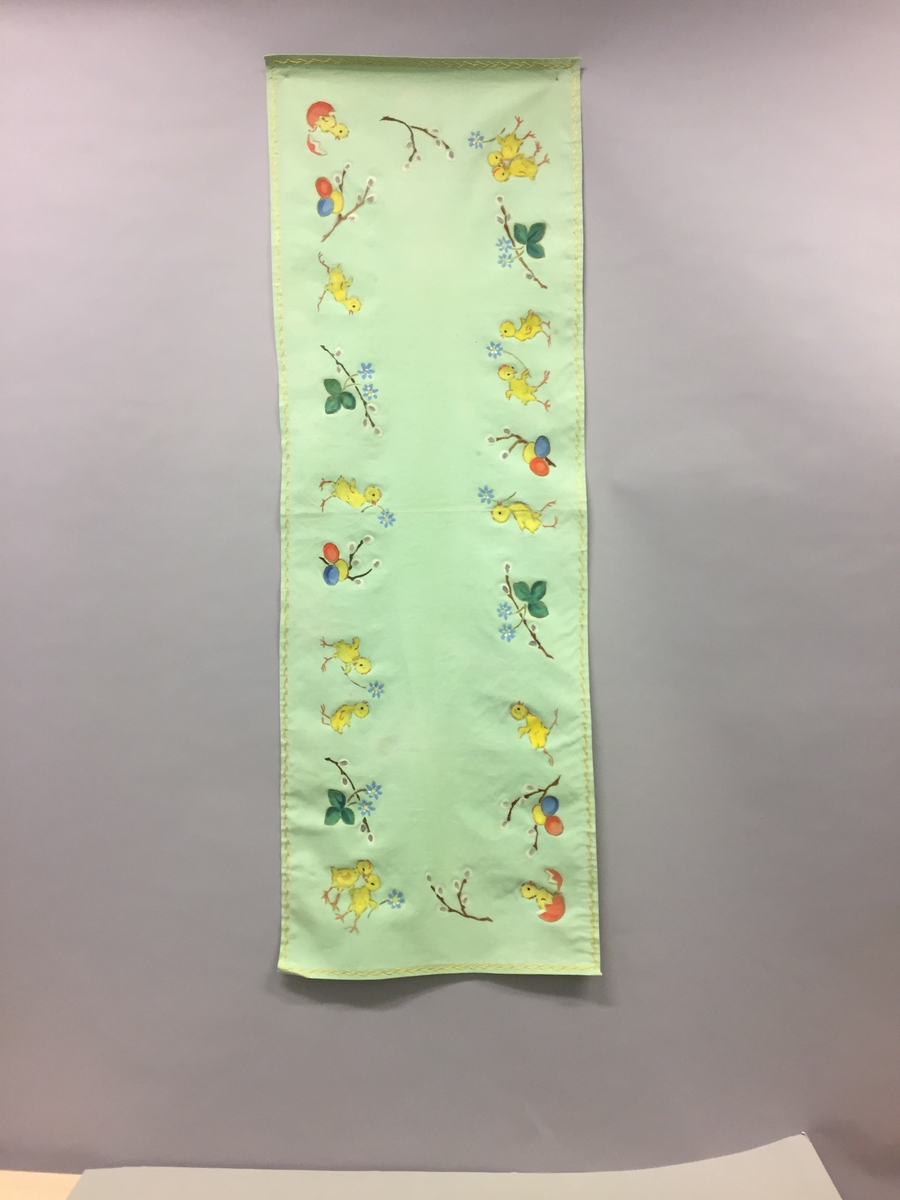 Løpar med trykt motiv. Kyllingar, blåveis og seljekvistar med "gåsungar". Handbrodert kant rundt alle sidene.
