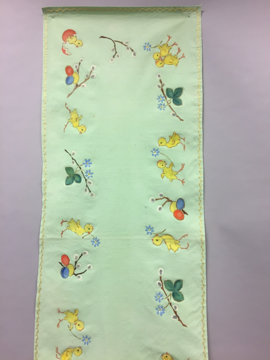 Løpar med trykt motiv. Kyllingar, blåveis og seljekvistar med "gåsungar". Handbrodert kant rundt alle sidene.