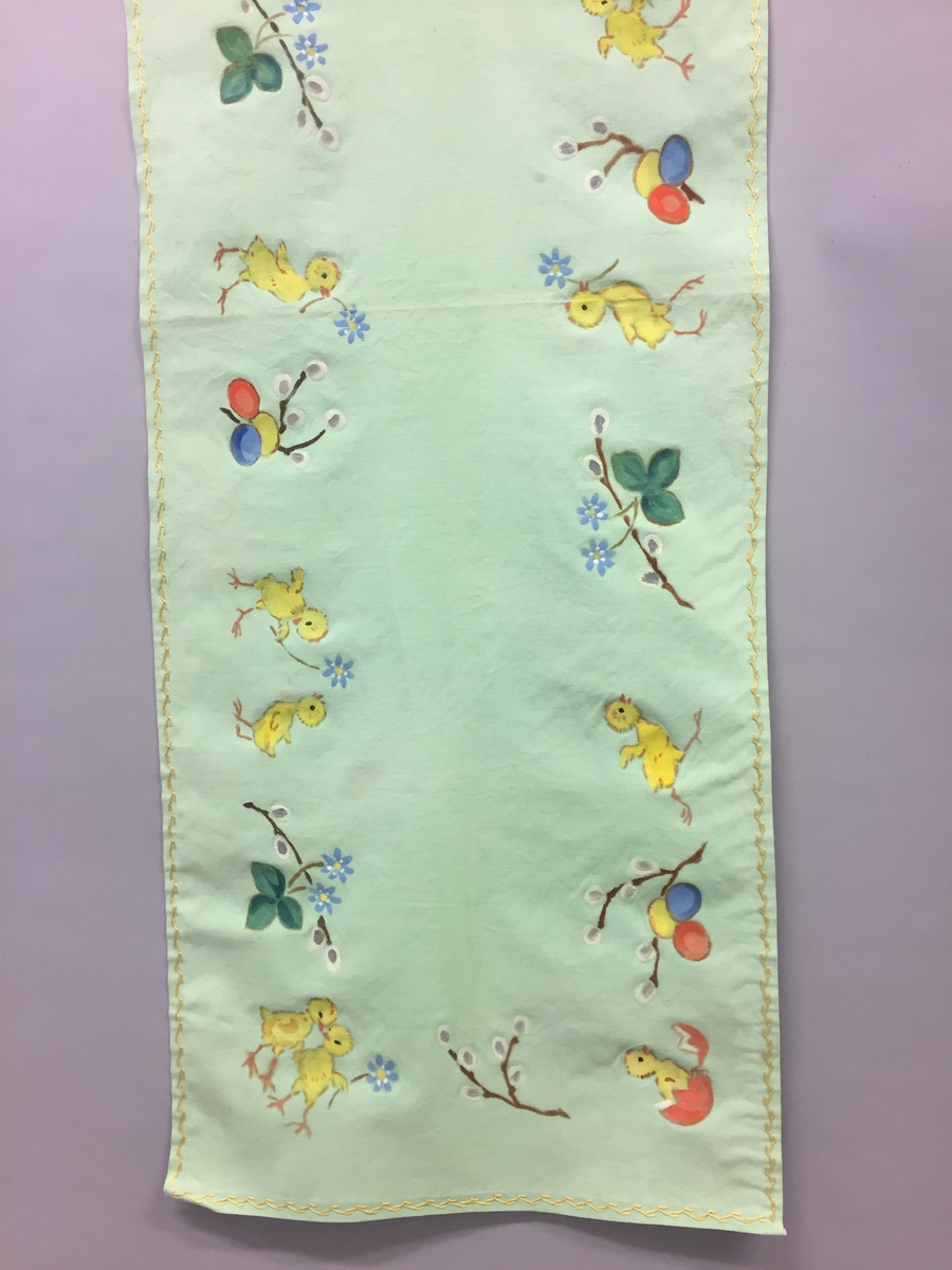 Løpar med trykt motiv. Kyllingar, blåveis og seljekvistar med "gåsungar". Handbrodert kant rundt alle sidene.