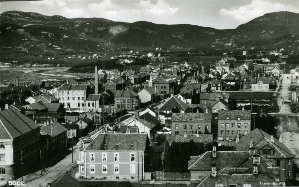 Postkort med motiv fra Bodø sentrum med Telegrafbygningen, Falckgården og Samfundet sentralt i bildet med Rønvikfjellet i bakgrunnen.