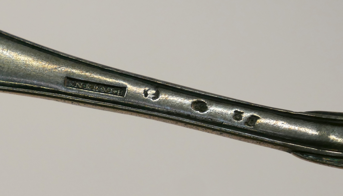 Ett etui med en uppsättning resebestick, kniv, gaffel och sked av silver. Kniv och gaffel med skaft av pärlemor.
Skeden dekorerad med monogram "FML" och stämplad med årsbokstav: F2=1788 samt "Eneroth" = guld- och silversmed Petter Eneroth (1741-1809) mästare från 1771.