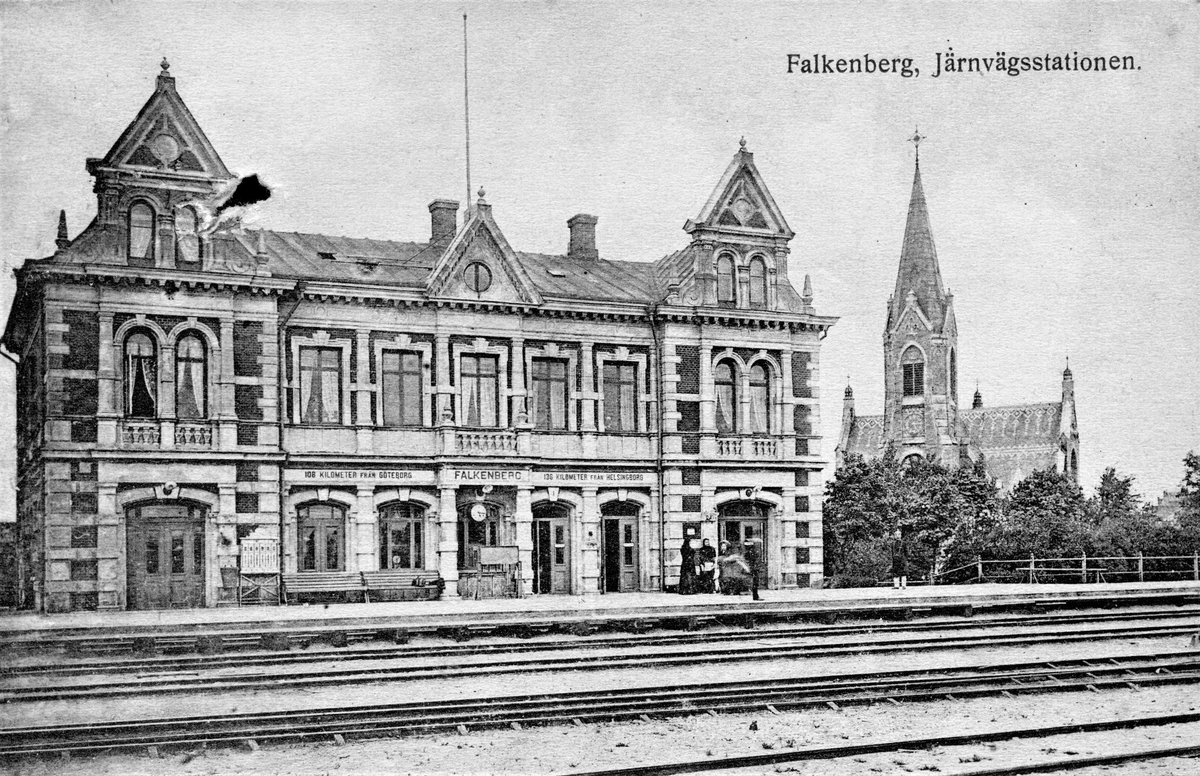 Vykort, "Falkenberg. Järnvägsstationen". Till höger ses stadens moderna kyrka från 1892. På stationshusen angavs ofta avstånd till andra orter. Här upplyses resenärerna om att de är 108 km från Göteborg och 136 km från Helsingborg.