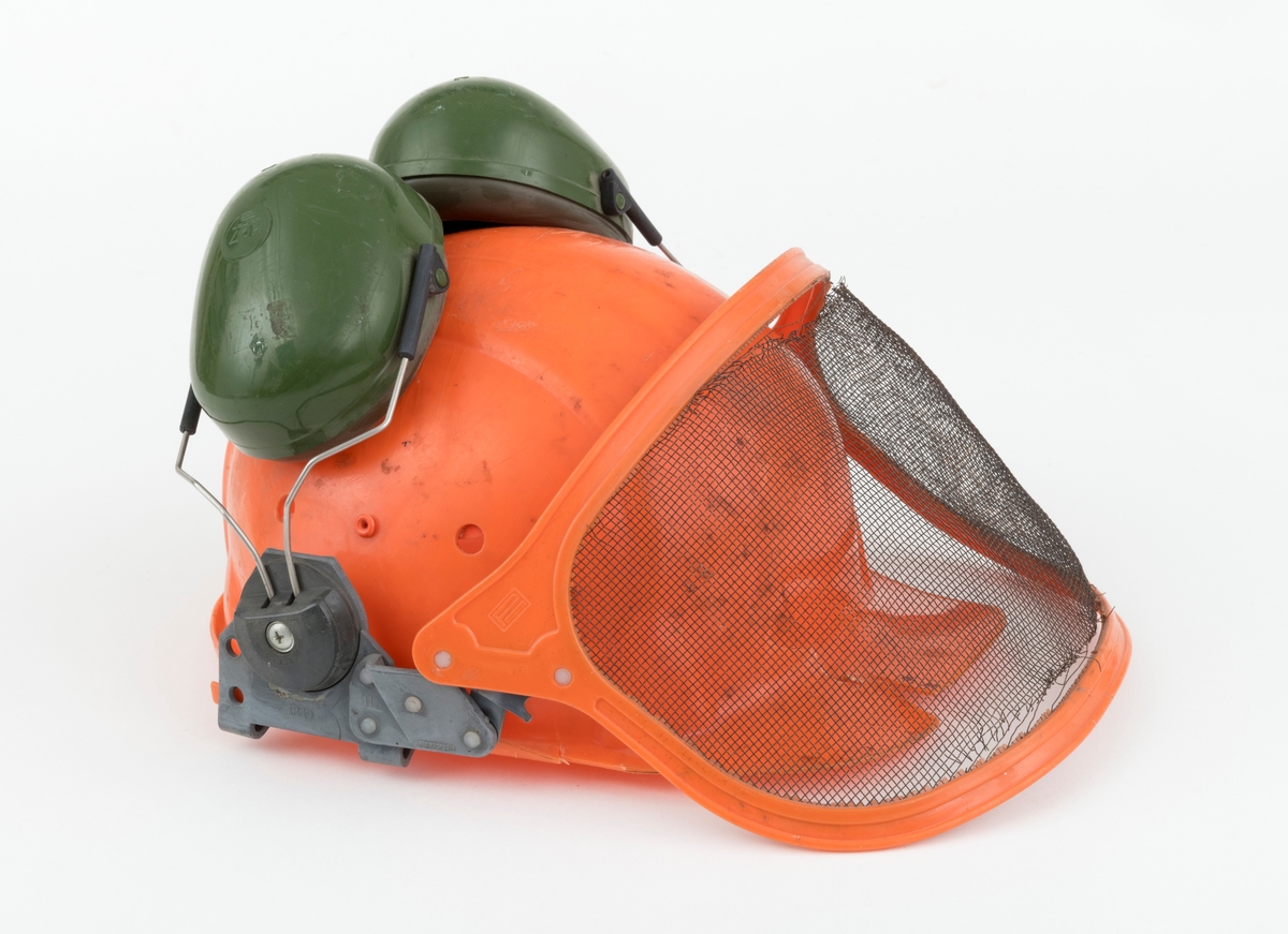 Hjelm, vernehjelm, hoggerhjelm, skogshjelm, for bruk under skogsarbeid. Hjelmen er støpt i hardplast. Den er utsyrt med visir og hørselvern (øreklokker). Det er flere sprekkdannelser hjelmens plastskall. Visirets netting har røket på to steder ved innfestingen i plastramma. Regulerbare reimer for tilpasning til brukerens hode mangler. 
Visir og hørselvern (øreklokker) er festet i samme "plastbrakett". Hørselvernene (øreklokkene) er regulerbare og kan svinges opp på hjelmen med en enkel håndbevegelse. (Hørselvern og visir kan for registrator se ut til å være av noe nyere dato enn selve hjelmen, men det er ikke bekreftet. ) Hørselvernene har for øvrig skomgummpolstring som ligger an mot brukerens ører. 
Hjelmen har to luftehull på hver side som kan åpnes og lukkes med vridbare plastklaffer. Klaffene betjenes fra innsiden.