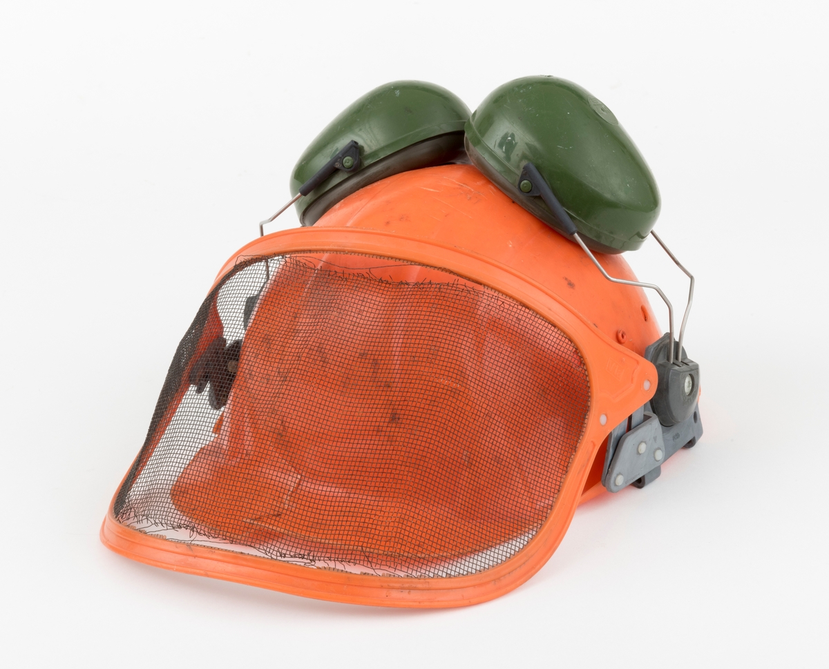 Hjelm, vernehjelm, hoggerhjelm, skogshjelm, for bruk under skogsarbeid. Hjelmen er støpt i hardplast. Den er utsyrt med visir og hørselvern (øreklokker). Det er flere sprekkdannelser hjelmens plastskall. Visirets netting har røket på to steder ved innfestingen i plastramma. Regulerbare reimer for tilpasning til brukerens hode mangler. 
Visir og hørselvern (øreklokker) er festet i samme "plastbrakett". Hørselvernene (øreklokkene) er regulerbare og kan svinges opp på hjelmen med en enkel håndbevegelse. (Hørselvern og visir kan for registrator se ut til å være av noe nyere dato enn selve hjelmen, men det er ikke bekreftet. ) Hørselvernene har for øvrig skomgummpolstring som ligger an mot brukerens ører. 
Hjelmen har to luftehull på hver side som kan åpnes og lukkes med vridbare plastklaffer. Klaffene betjenes fra innsiden.