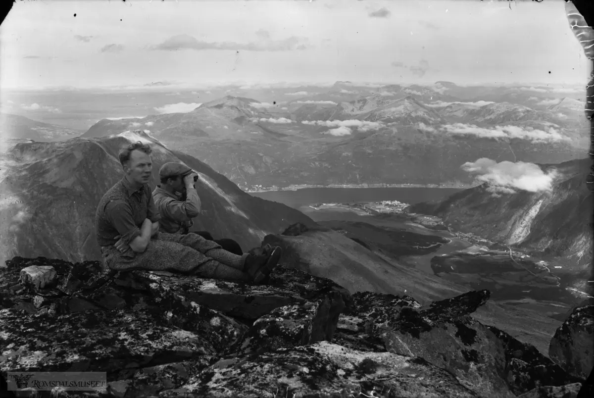 Frå Store Trolltind. Nedre delen av Romsdalen med elva Rauma og Åndalsnes, Romsdalsfjorden og Stranda på andre sida med Hegerholmen, Skorga og Skorgedalen. Bak karane: Setnesfjellet. Personen nærast kamera: Herleik Heramb-Aamot.