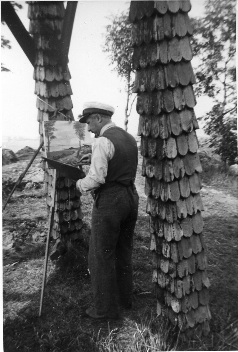 En man i vit skjorta, väst och skepparmössa står under en klockstapel och målar. Motivet, på staffliet, visar utsikten. I vänster hand håller han en palett.
