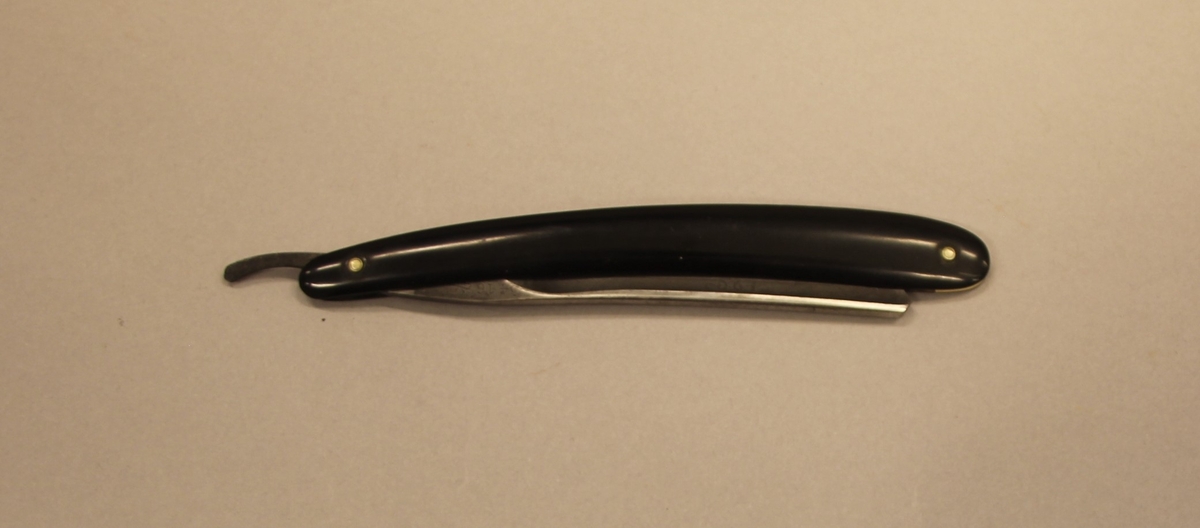 Barberkniv til å falde saman. Plastskaft. Ligg i eit etui av papp. "Damaskus" på bladet.