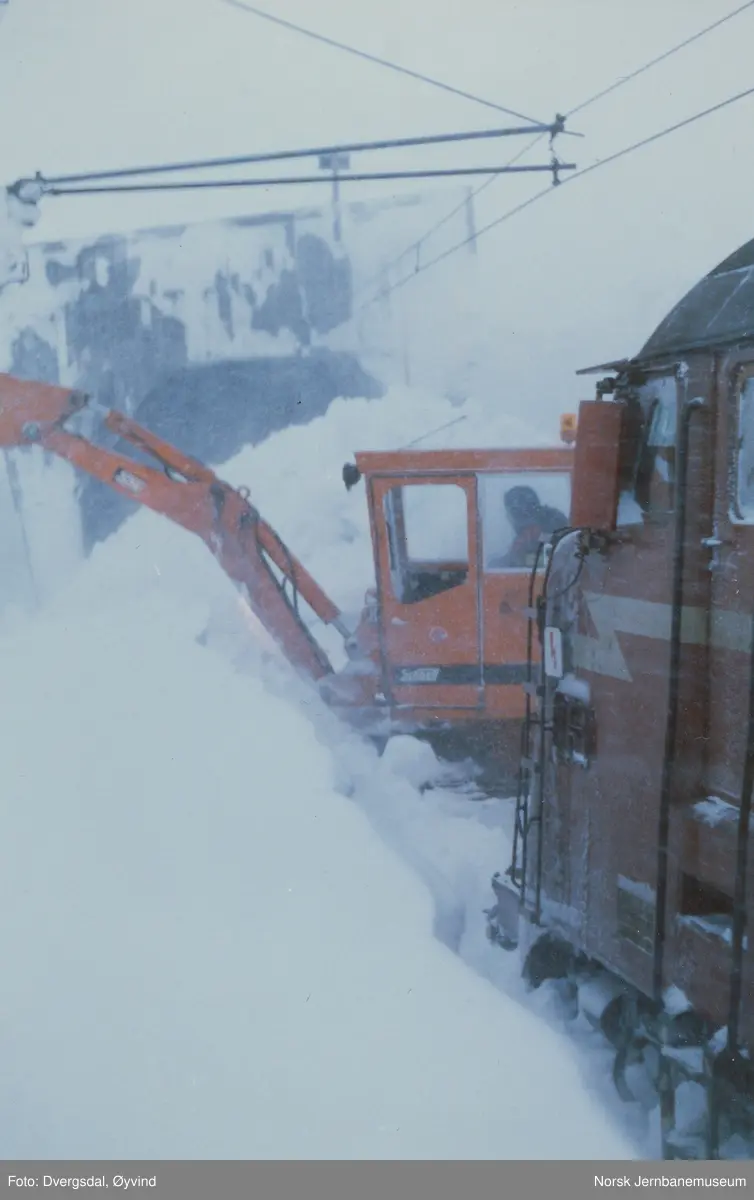 Snørydding med gravemaskin mellom Finse og Taugevatn. Høye brøytekanter ble gravd ned i sporet med gravemaskin og deretter fjernet med roterende snøplog