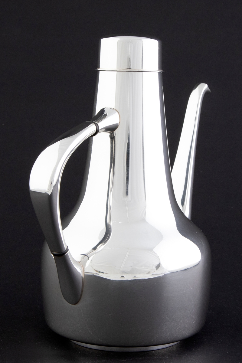 Kaffekanne som er utført i glattpolert sølv, uten dekor og med myke kanter. Sylinderformet kompakt korpus, som glir over i en konisk langstrakt hals. Fra korpus løper en lang tynn tut, som er mykt buet. Det sirkulære lokket fremstår som en forlengelse av halsen, men overgangen er anntydet med en ringformet vulst. Den buede haken løper fra korpus til øvre del av halsen, og før ansatsene er det plassert to ringformede lameller av presstoff for varmeisolering. 