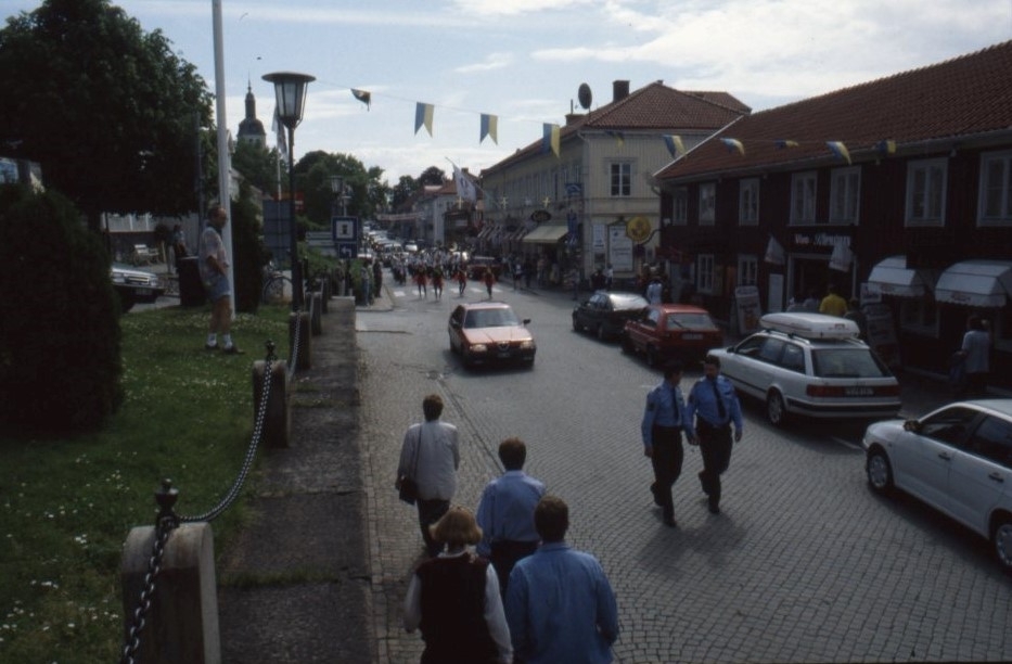 Vy över Brahegatan där en paraderande orkester rör sig mot norr. Två poliser går före orkestern.