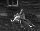 Man sitter i gräset med hund, Förer Erik Larsson