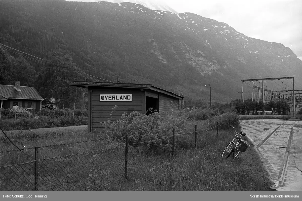 Øverland holdeplass med friluften i bakgrunnen og bolig på sørsiden av jernbanesporet.